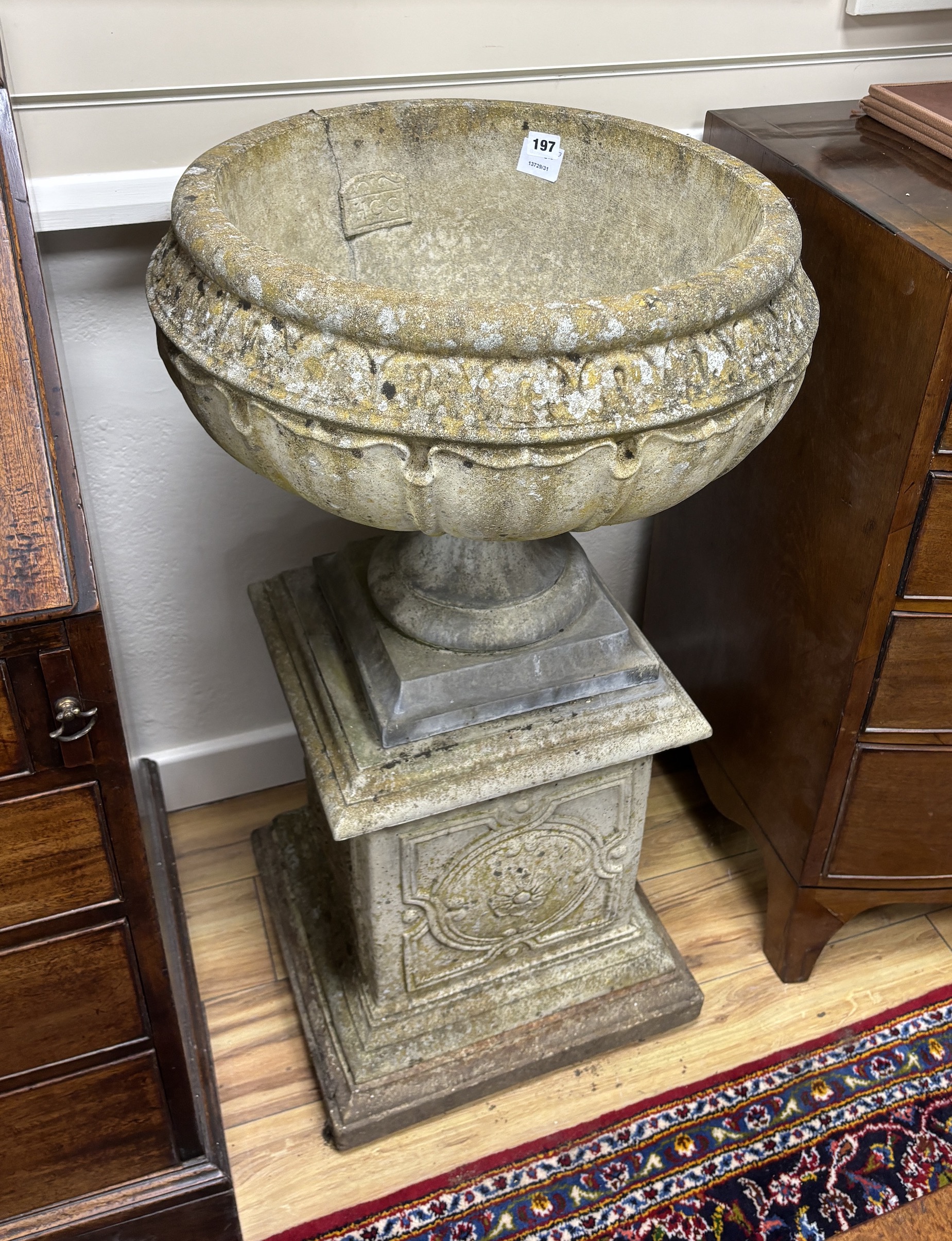 A set of three circular reconstituted stone garden urns on square plinths, diameter 54cm, height 95cm
